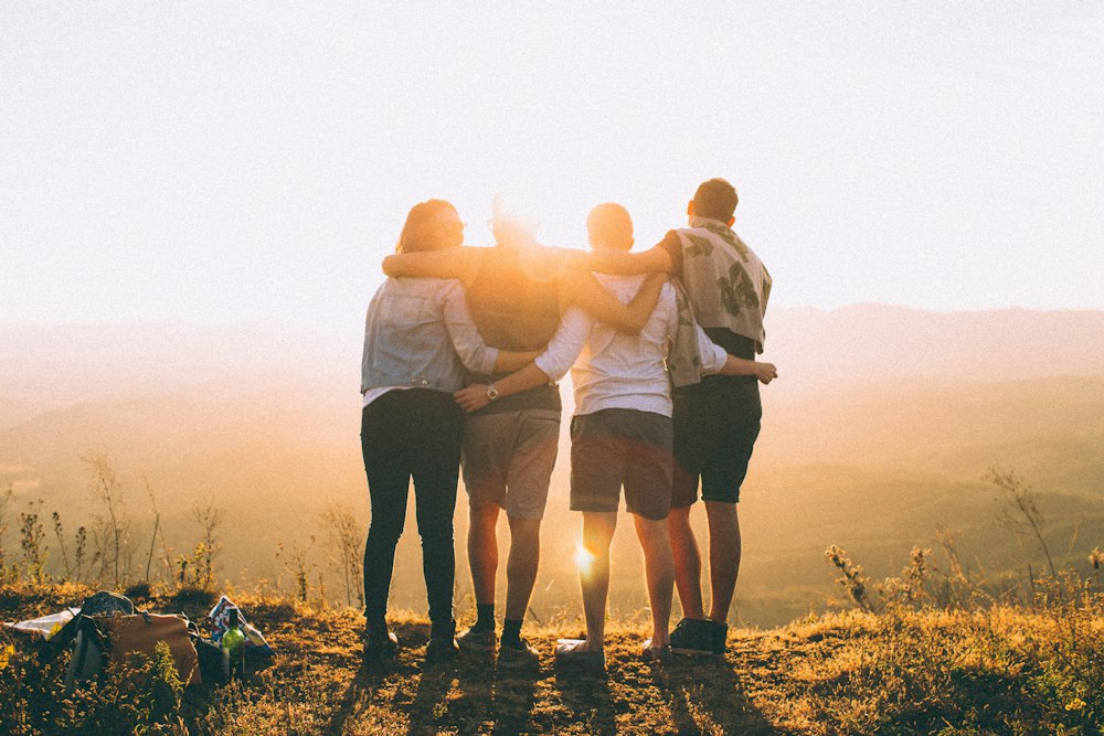 Group of friends hugging while watching a sunset